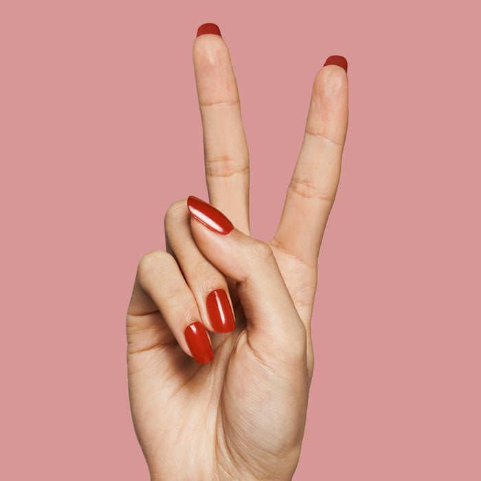 CV - Press-On | Medium | Squoval bright cherry red medium squoval false nails on hand against muted pink background