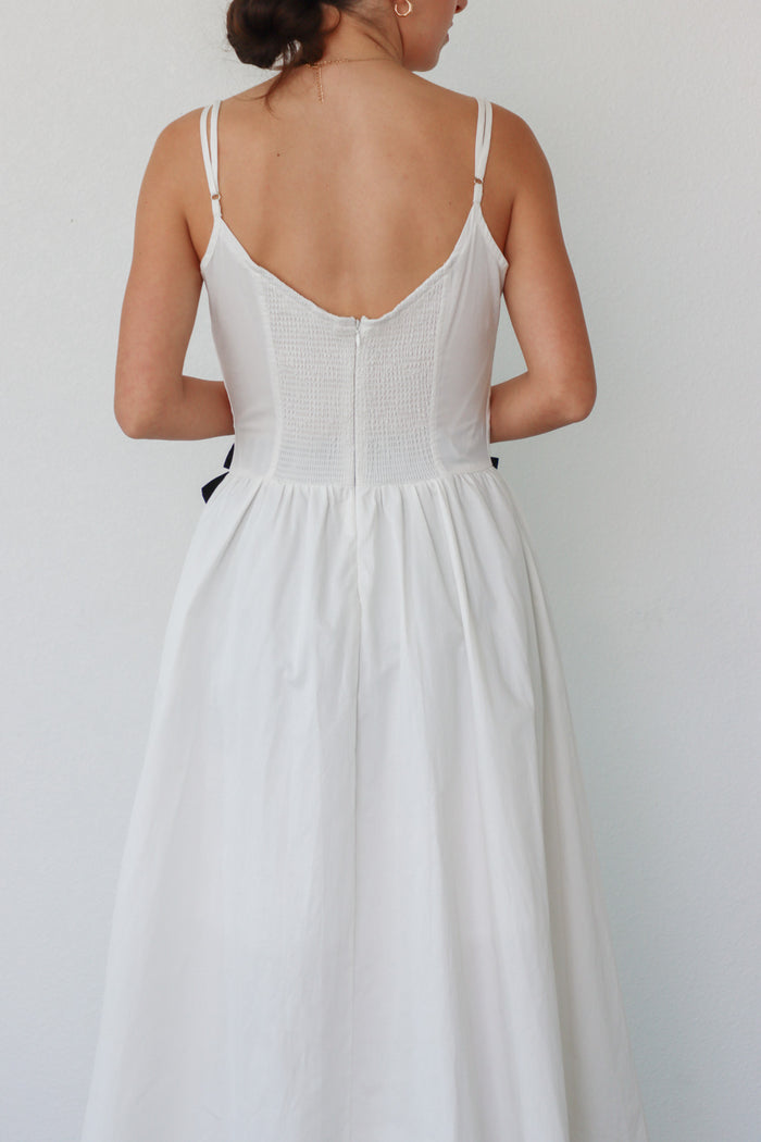 girl wearing white long dress with black bow details