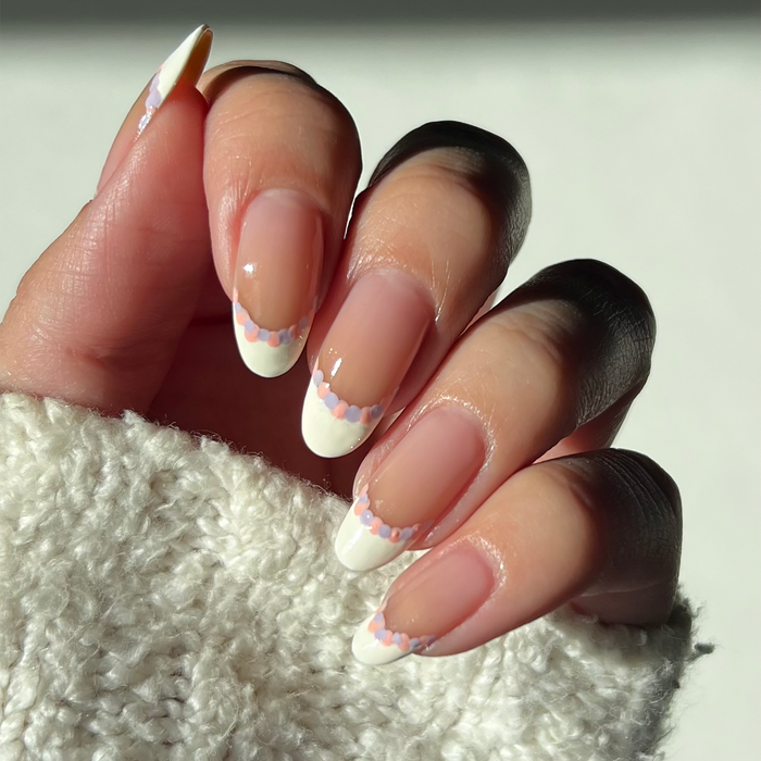 Lavender Drop pastel French tip nail art on a deep skin tone with a white sweater