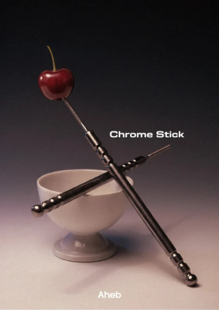A pair of metallic chrome sticks with decorative ball accents and a small stem, crossed over a white pedestal bowl on a dark gradient background. The text 'Chrome Stick' and 'Aheb' are visible on the image.