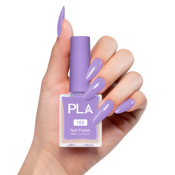 Hand holding a purple nail polish bottle with matching nails on a white background