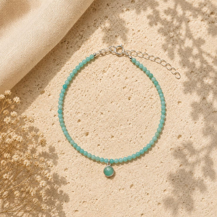 Turquoise beaded bracelet with a silver clasp on a beige surface with dried flowers.