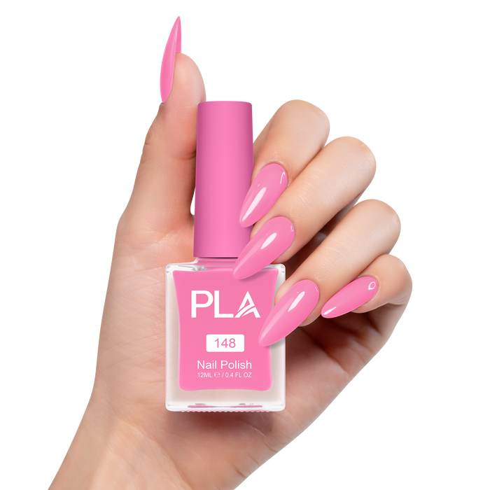 Hand holding a pink nail polish bottle with matching nails on a white background