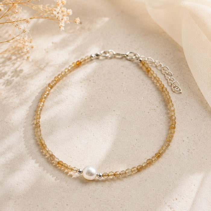 Delicate bracelet with small beads and a pearl on a beige fabric background