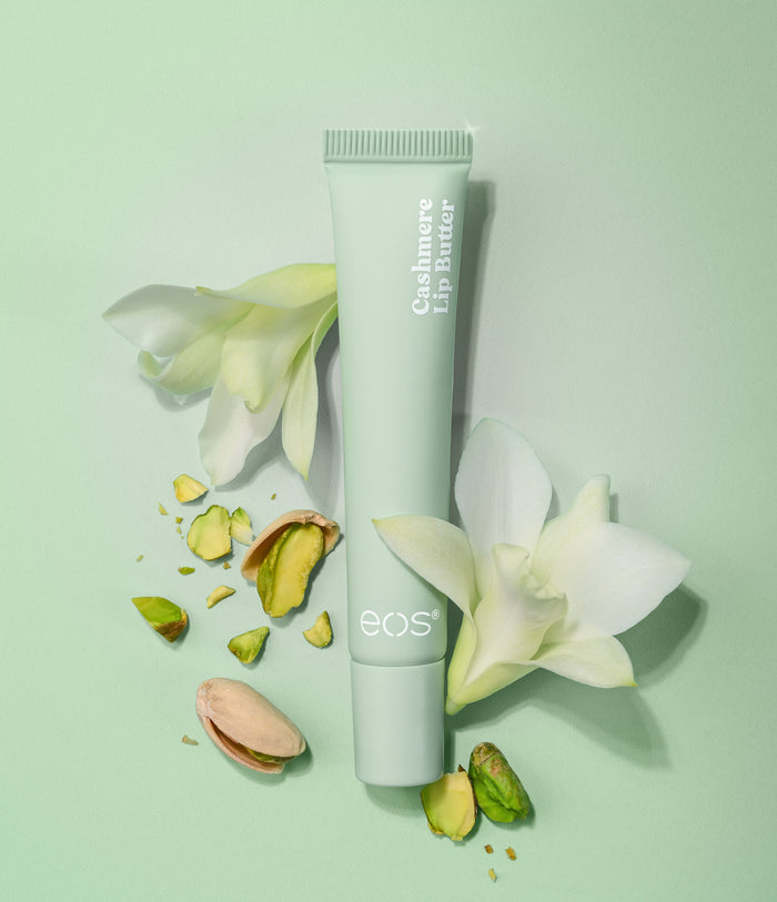 eos Cashmere Lip Balm tube with flowers and pistachios on a light green background