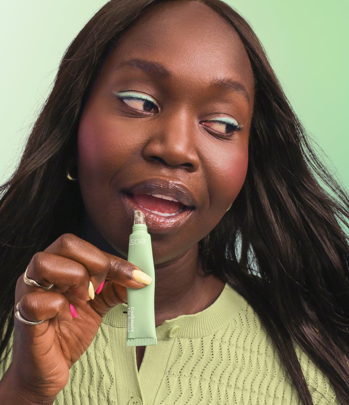 Woman holding a green skincare product against a light green background