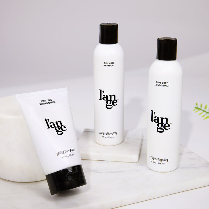 L’ange Curl Care shampoo, conditioner, and styling cream displayed on a marble surface.