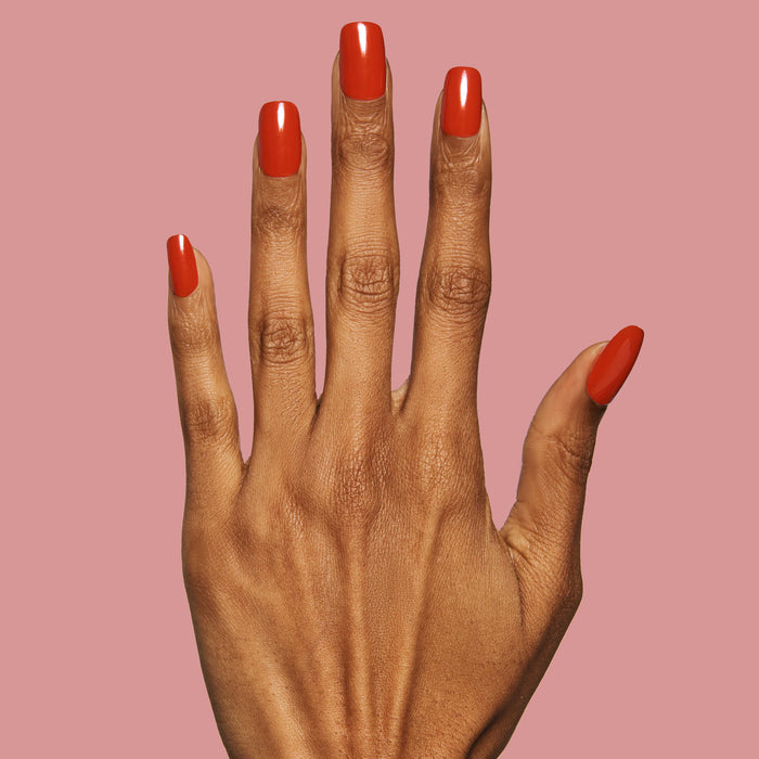 CV - Press-On | Medium | Squoval medium false nails in bright cherry red on hand with natural skin tone on pink background