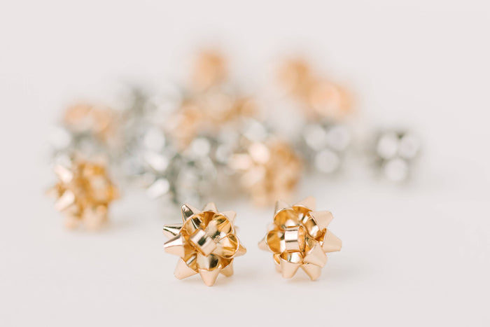 Gold Present Bow Earrings by St Armands Designs of Sarasota featuring elegant bow-shaped jewelry with a shiny gold finish.
