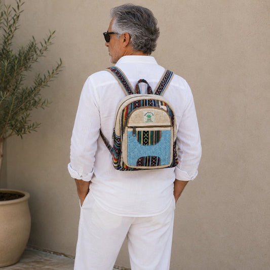 Man wearing a colorful backpack against a beige wall