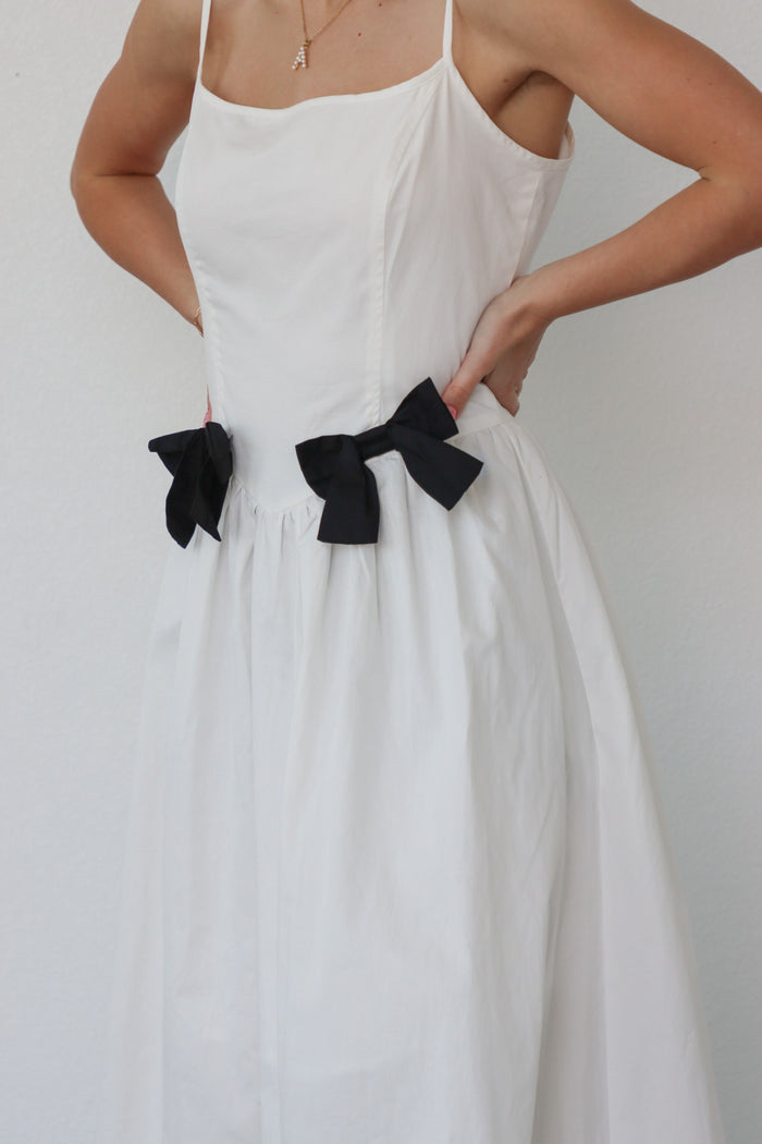 girl wearing white long dress with black bow details