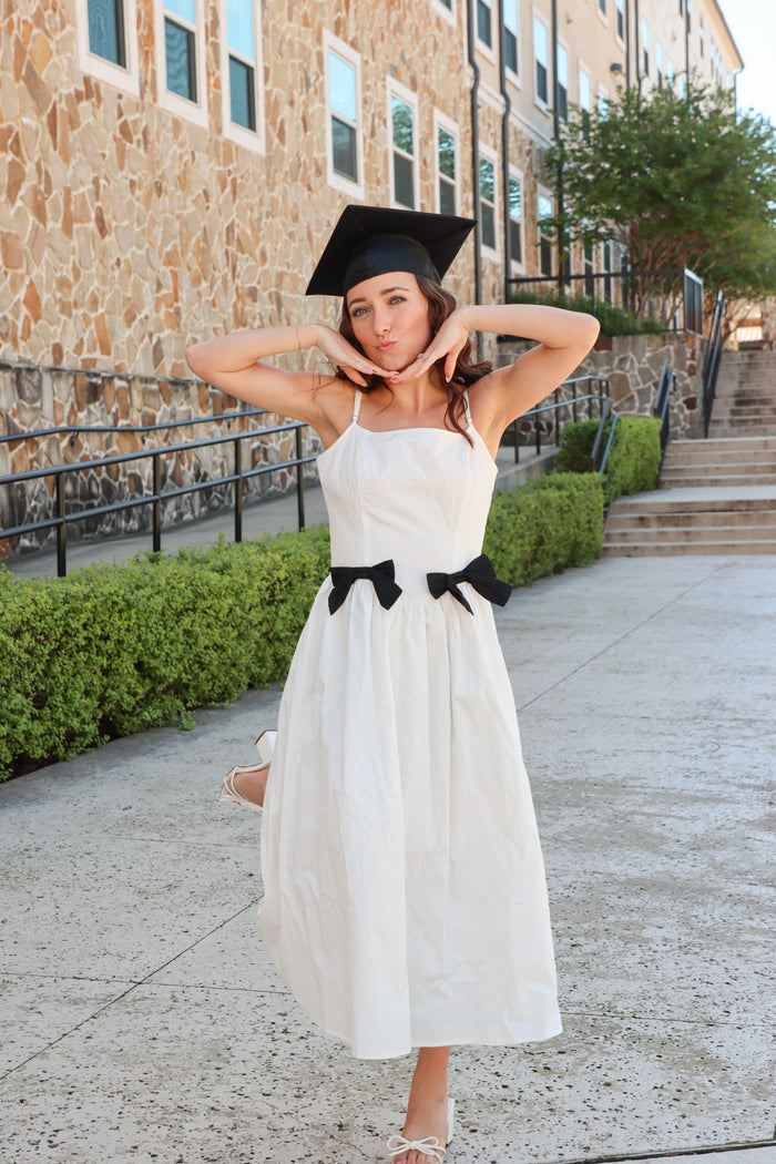 girl wearing white long dress with black bow details