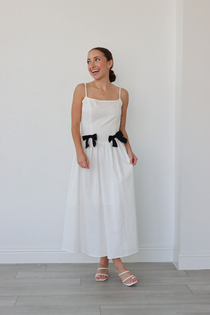 girl wearing white long dress with black bow details