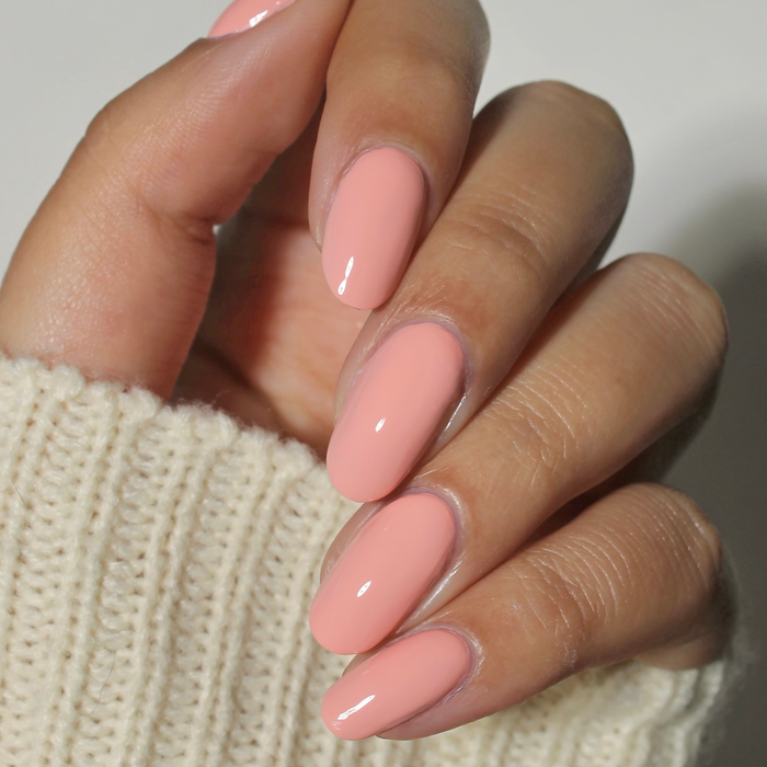 Just Peachy pastel coral pink nail polish manicure on a medium skin tone with a white sweater