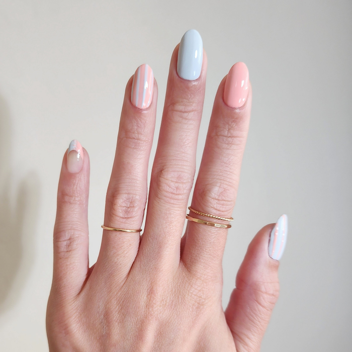 Just Peachy pastel pink nail polish with a blue accent nail on a light skin tone with rings