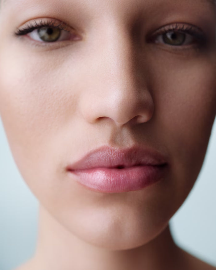Bare lips with La Mer The Lip Treatment in various shades, showcasing a luxurious beauty product in a new, unopened condition.