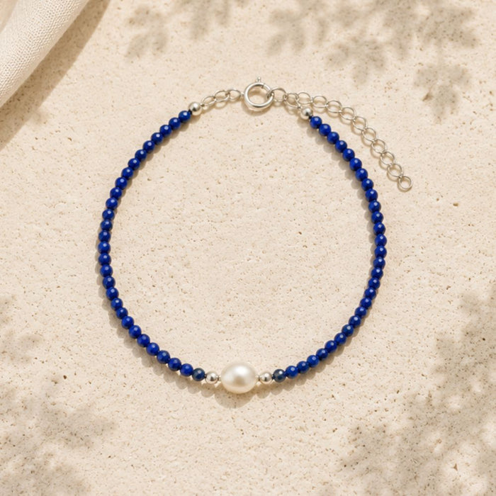 Blue beaded bracelet with a pearl on a beige fabric background