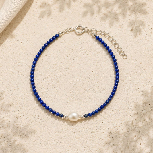 Blue beaded bracelet with a pearl on a beige fabric background