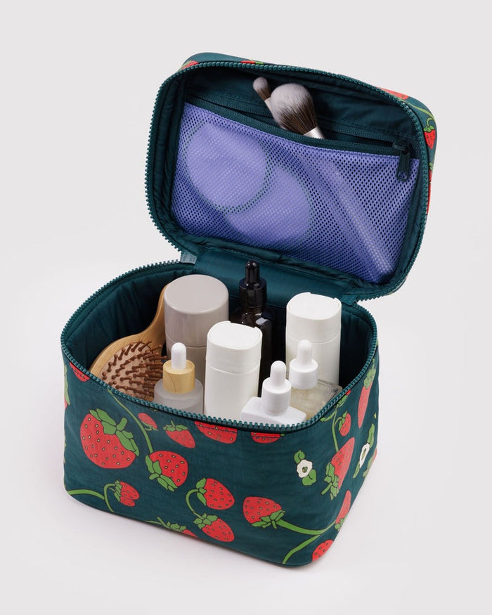 Large strawberry-print cosmetic case open with organizer pockets and bottles inside.