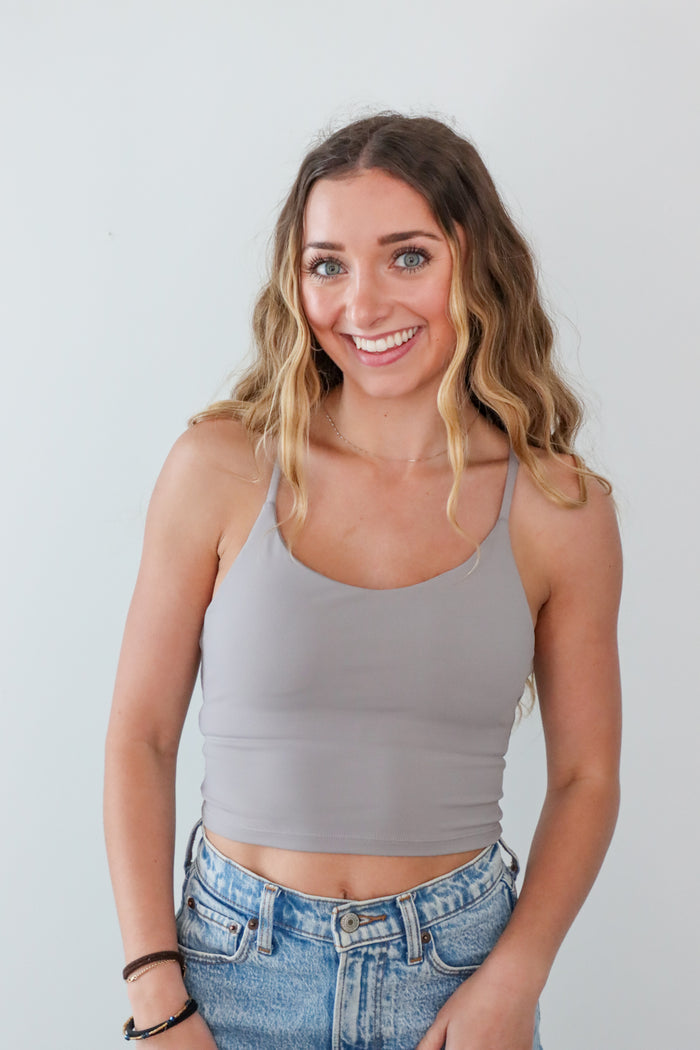 Woman wearing a gray tank top and blue jeans against a plain background