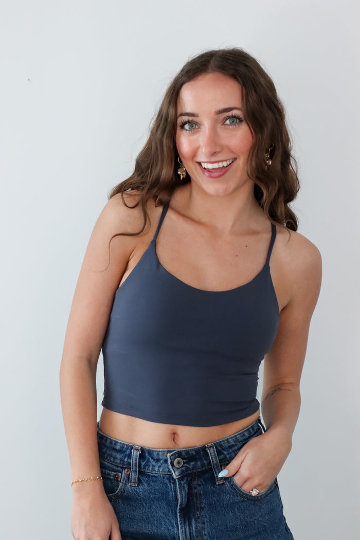 Woman wearing a dark blue crop top and jeans against a plain background