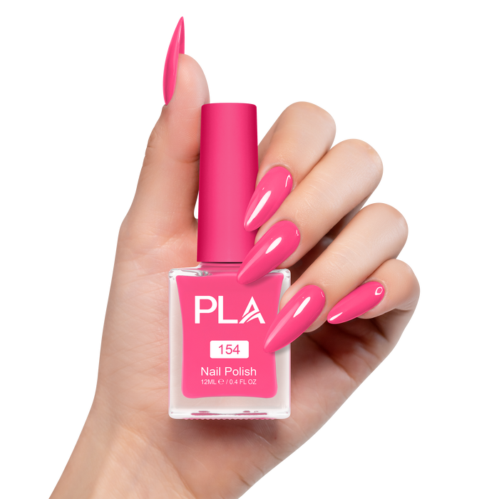 Hand holding a pink nail polish bottle with matching nails on a white background