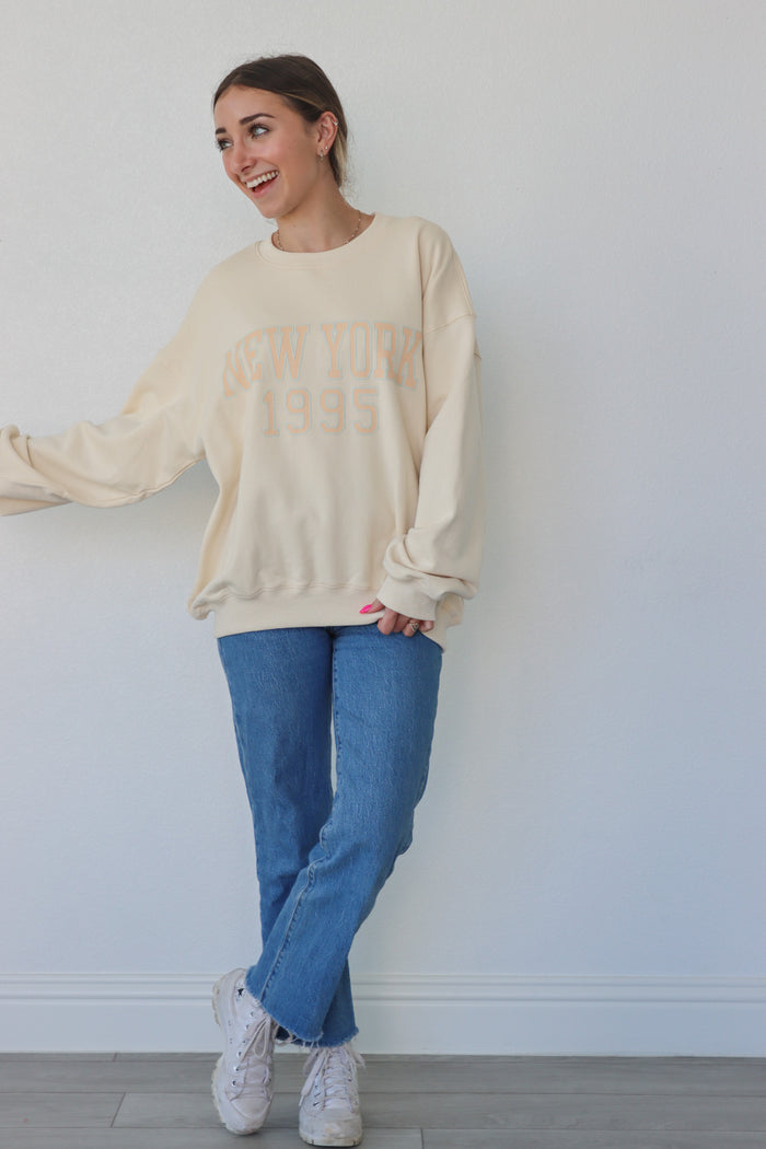 girl wearing cream "new york 1995" crewneck
