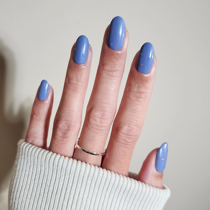 Pearl Drops satin finish over periwinkle blue nail polish on a light skin tone