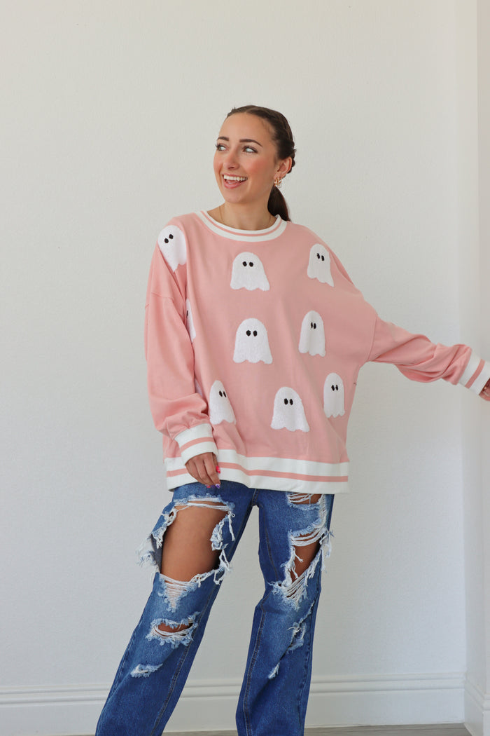 girl wearing pink crewneck with ghost patches