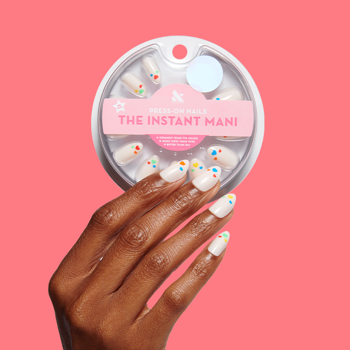 Hand with Rainbow Love | Almond | Medium press-on nails in neutral shade with multi-colored heart design against pink background