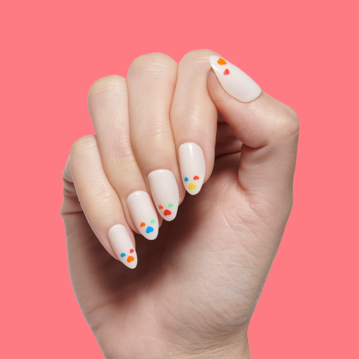 Hand with Rainbow Love | Almond | Medium press-on nails in neutral shade featuring colorful scattered hearts on pink background