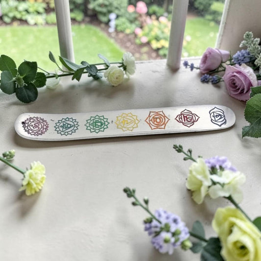Seven Chakras Engraved Incense Stick Burner on a windowsill with flowers