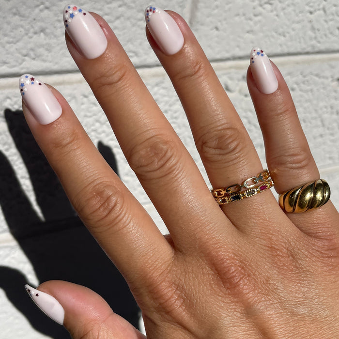Star Showers | Almond | Medium press-on nails with festive tiny stars on almond-shaped French tip manicure