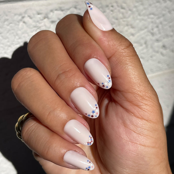 Star Showers | Almond | Medium press-on manicure with medium almond shape and tiny red, white, and blue star French tips design