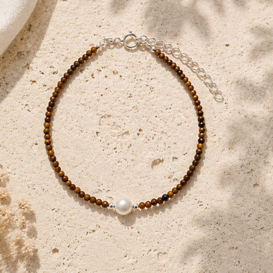 Beaded bracelet with a pearl on a sandy surface