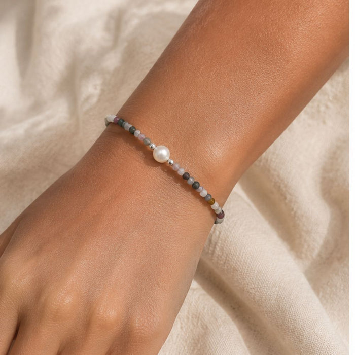 Pearl bracelet on a wrist against a neutral background